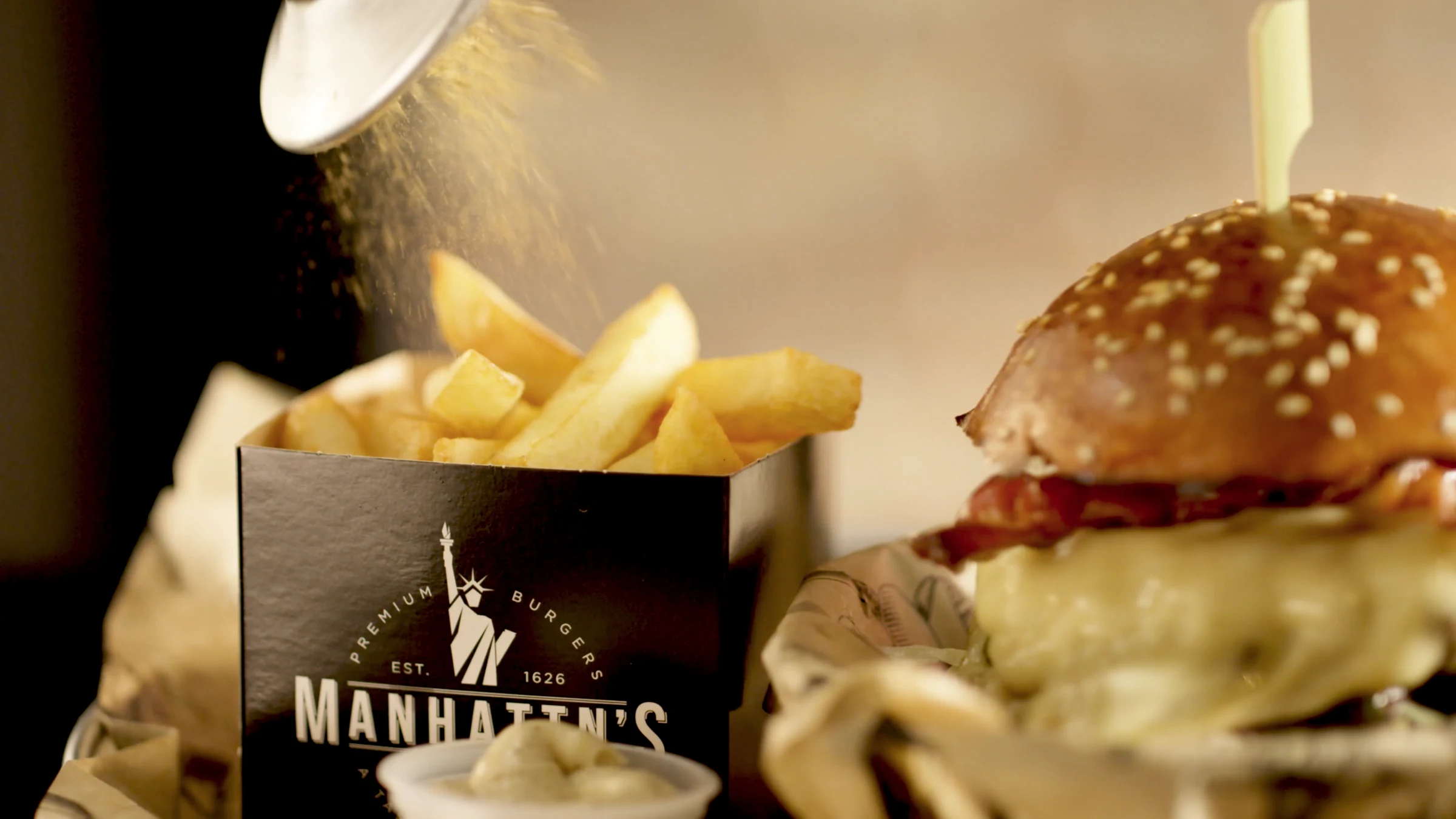 Seasoning fries beside a freshly prepared burger