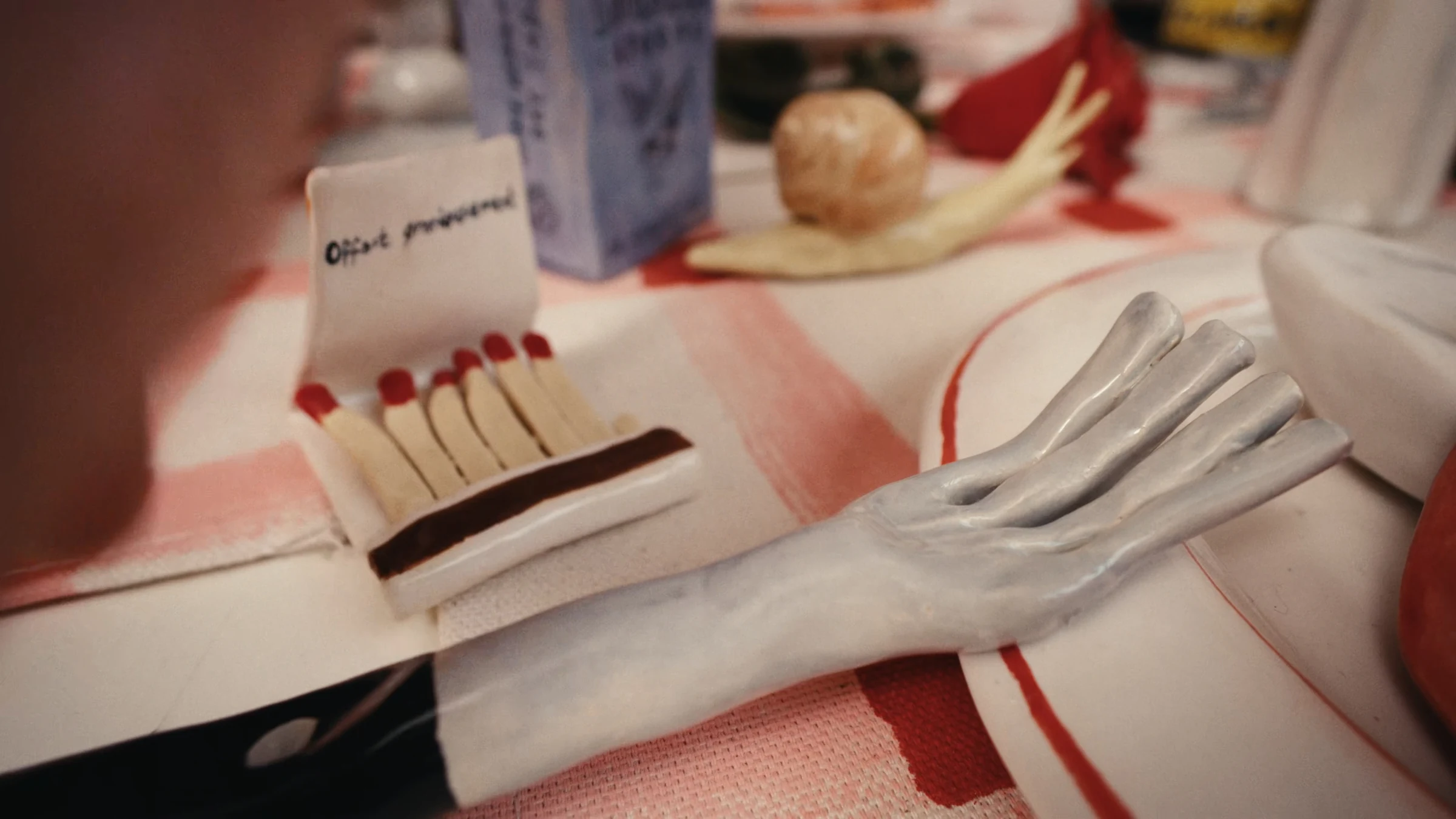 Ceramic matches and cutlery on a patterned table