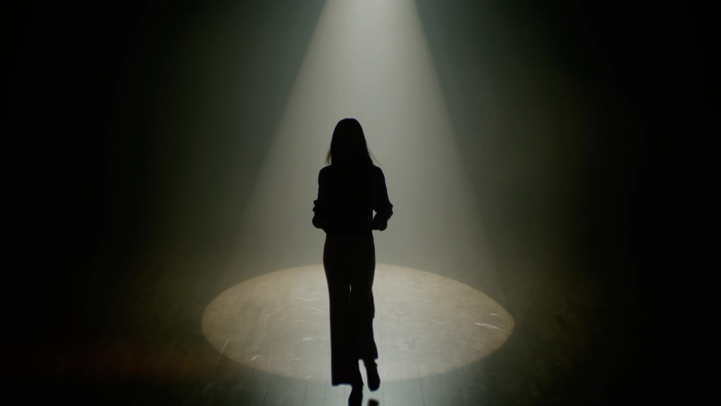 Silhouette walking into a pool of light